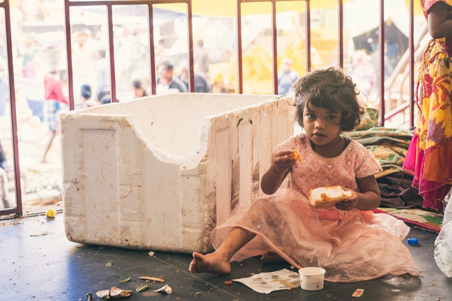 A young girl sitting on the ground eating a meal