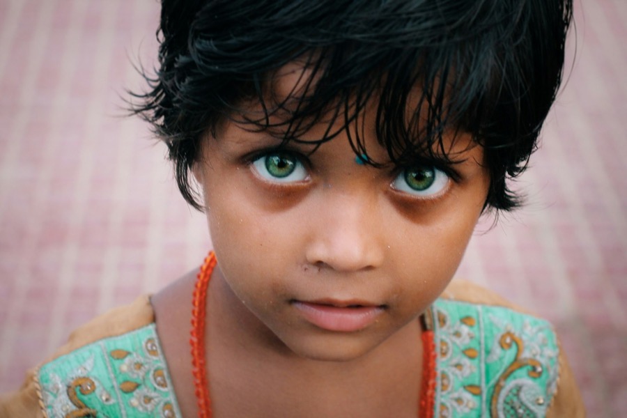 A young Tamil girl in an orange floral top looking at the camera