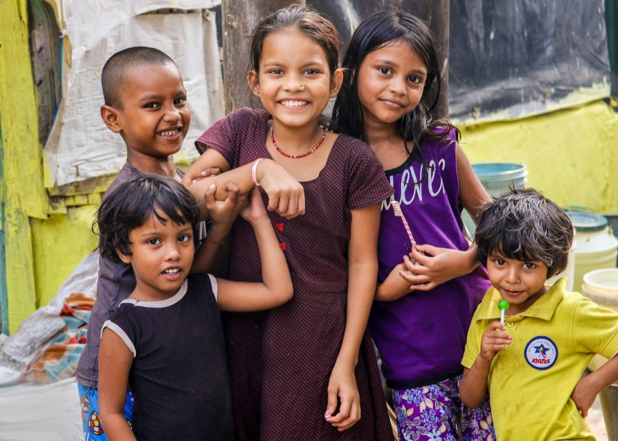 Five children smiling together in a village lane