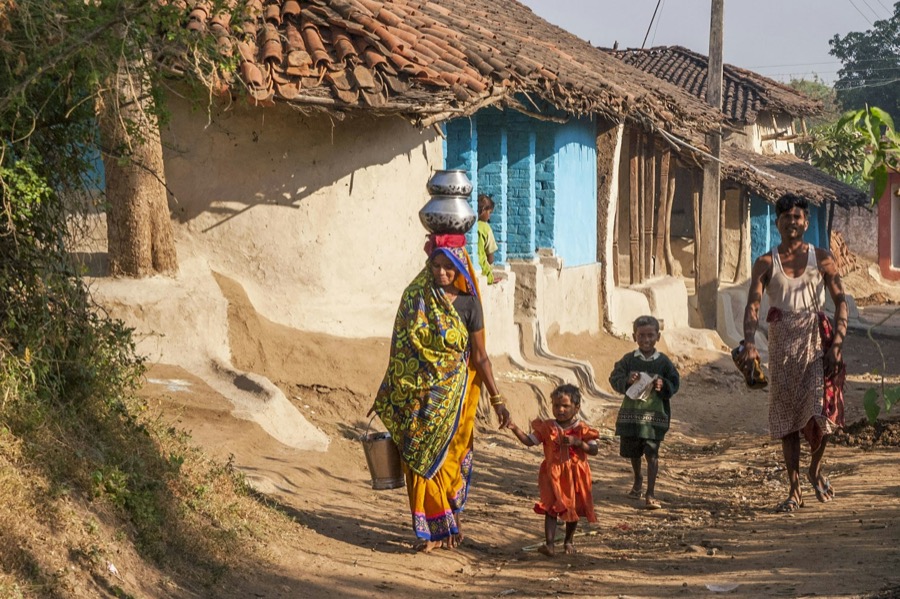 A woman and children walking down a lane between village homes
